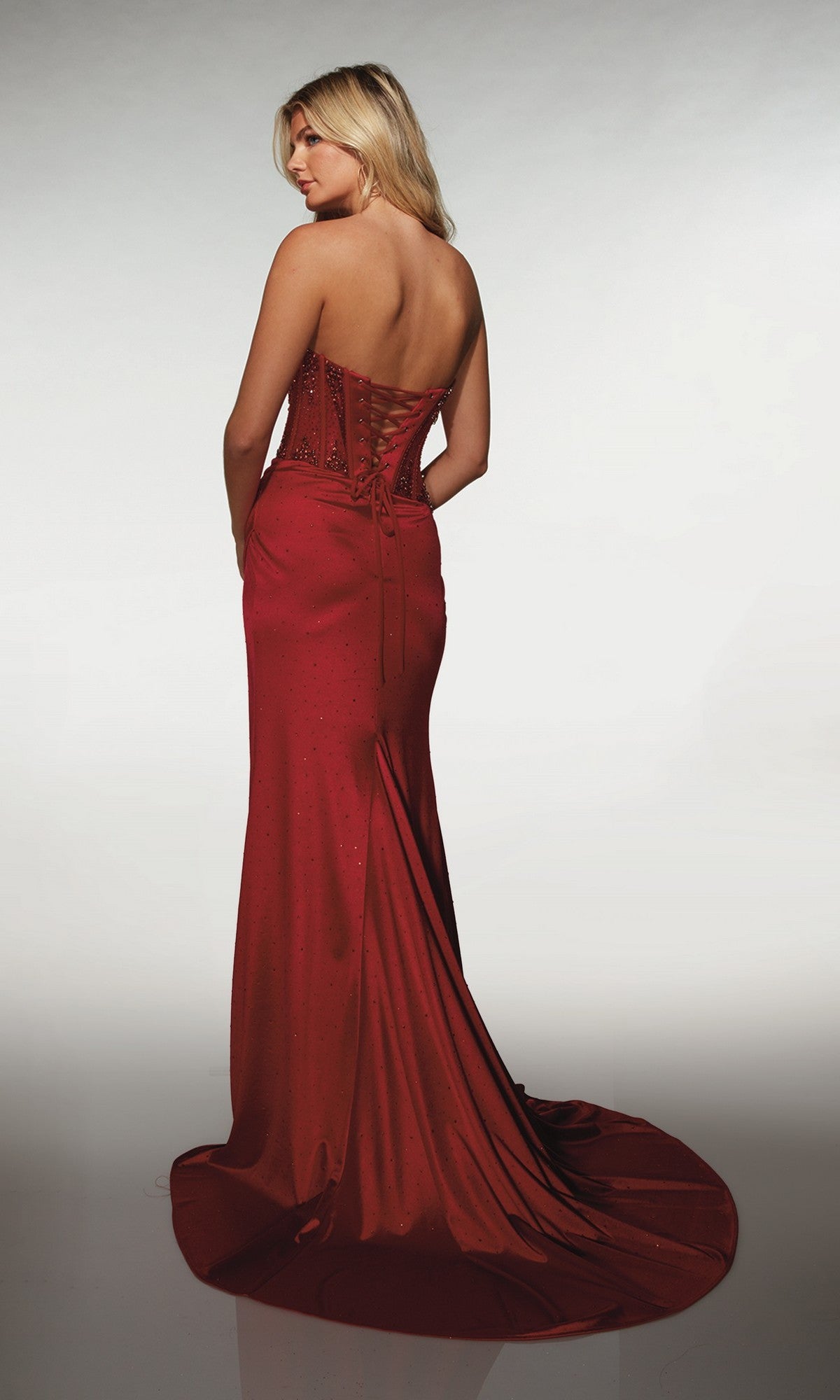 A woman poses on a white background in the Alyce 62147, a strapless long formal dress with a beaded corset bodice, lace-up back, and dramatic floor-length train.